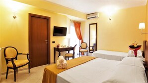 Une chambre d’hôtel avec deux lits, un bureau, une chaise, une télévision et un appareil de climatisation.