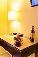 Un tavolo con due bicchieri da vino, una bottiglia di vino, una lampada e un composizione floreale decorativa.