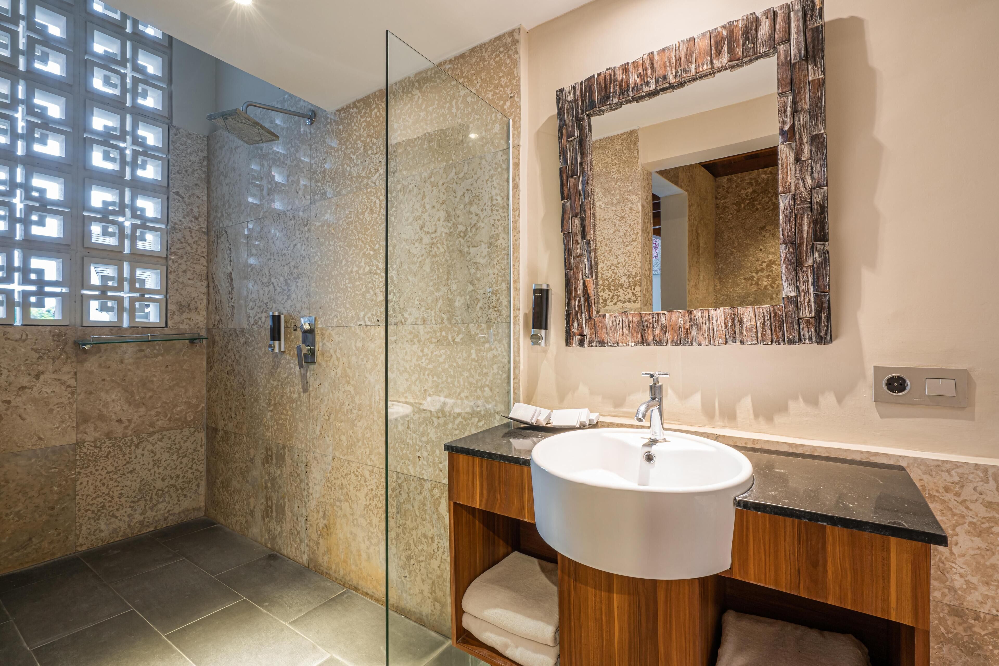 A modern bathroom with a glass-enclosed shower, a wooden vanity with a white sink, and a large mirror with a rustic frame.