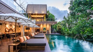 A modern poolside area with lounge seating and a dining area. - Pandawa All Suite Hotel (Kerobokan)