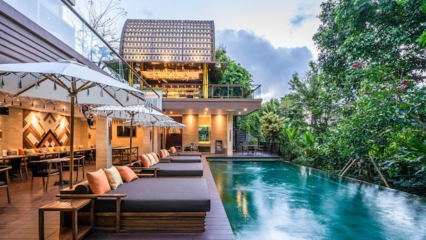 A modern poolside area with lounge seating and a dining area. - Pandawa All Suite Hotel (Kerobokan)