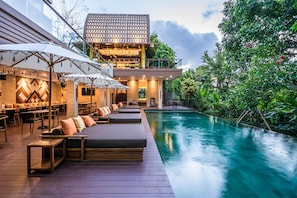 A modern poolside area with lounge seating and a dining area. - Pandawa All Suite Hotel (Kerobokan)