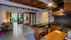 A modern kitchen with wooden cabinetry, a black countertop, and a stainless steel sink. - Pandawa All Suite Hotel (Kerobokan)