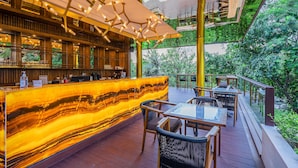 A modern outdoor bar area with a marble countertop, wooden seating, and a view of lush greenery. - Pandawa All Suite Hotel (Kerobokan)