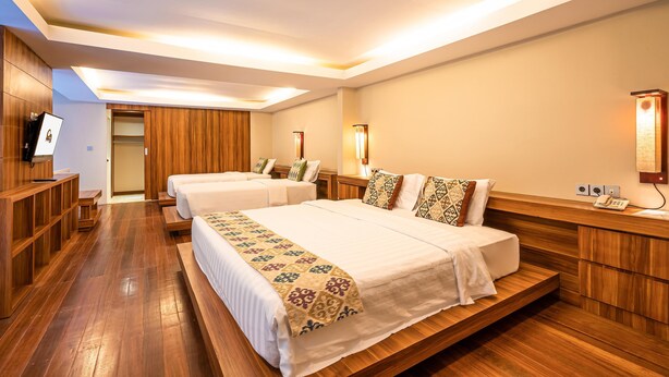 A hotel room with two beds, wooden flooring, a TV, and a desk. - Pandawa All Suite Hotel (Kerobokan)
