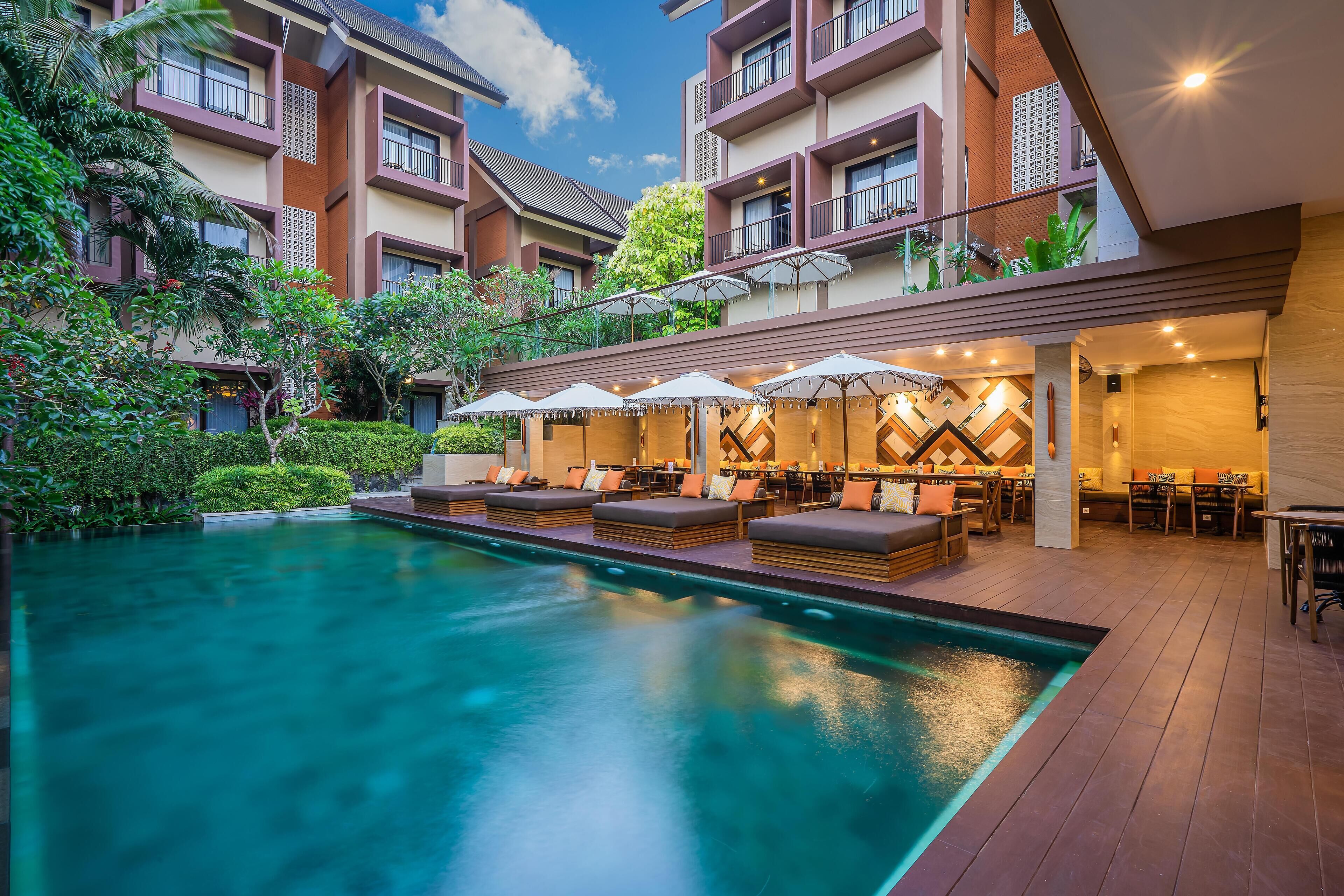 A hotel with a swimming pool, outdoor seating, and a well-maintained garden.