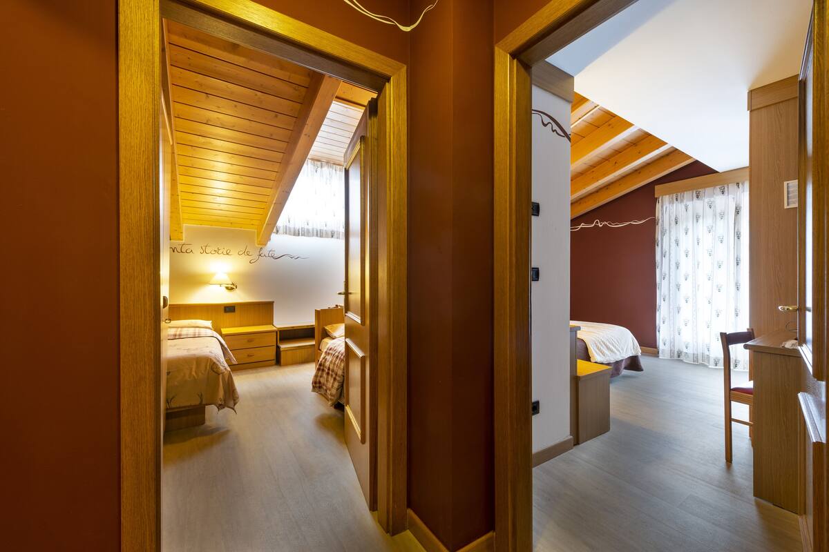 A bedroom with a wooden ceiling, a bed, a nightstand, and a window with curtains.