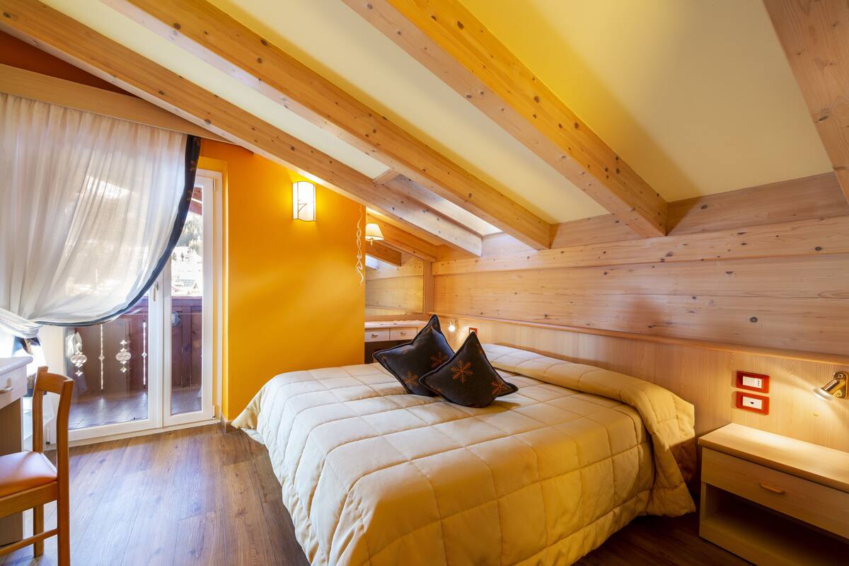 A bedroom with a bed, a chair, a nightstand, and a window with curtains.