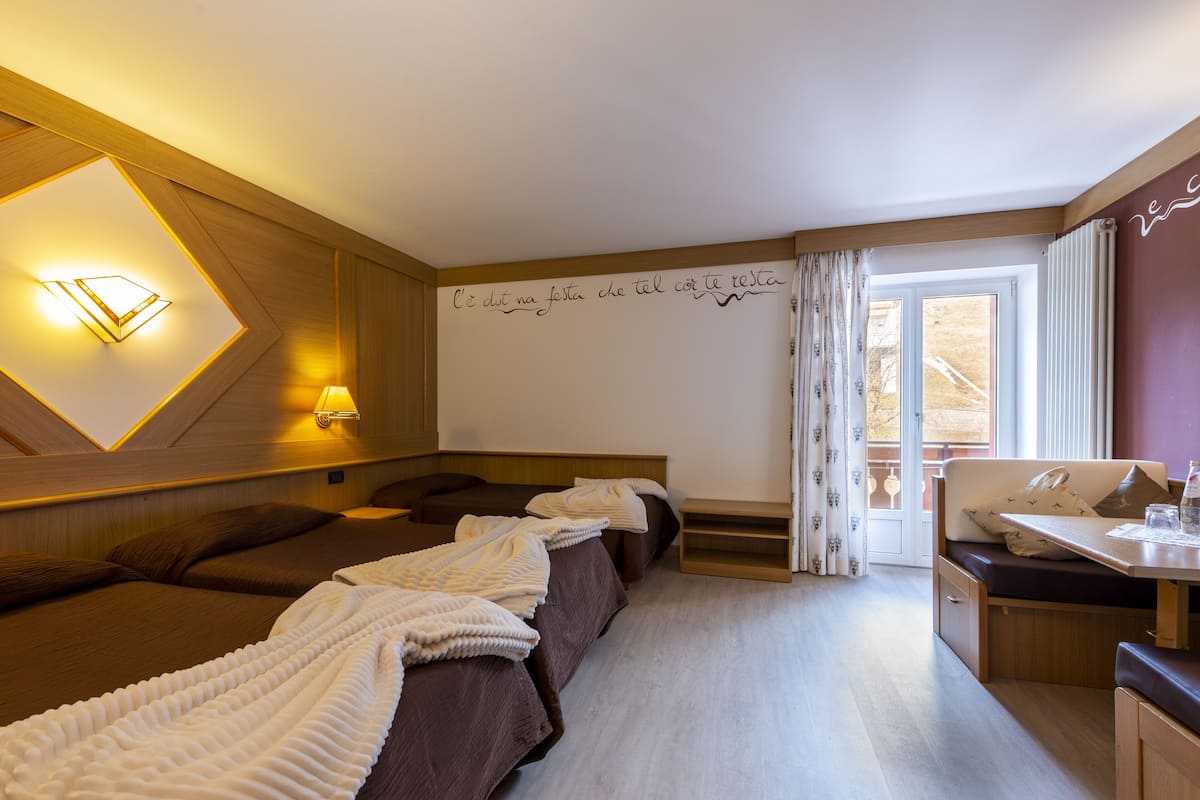 A hotel room with two beds, a desk, and a window with curtains.