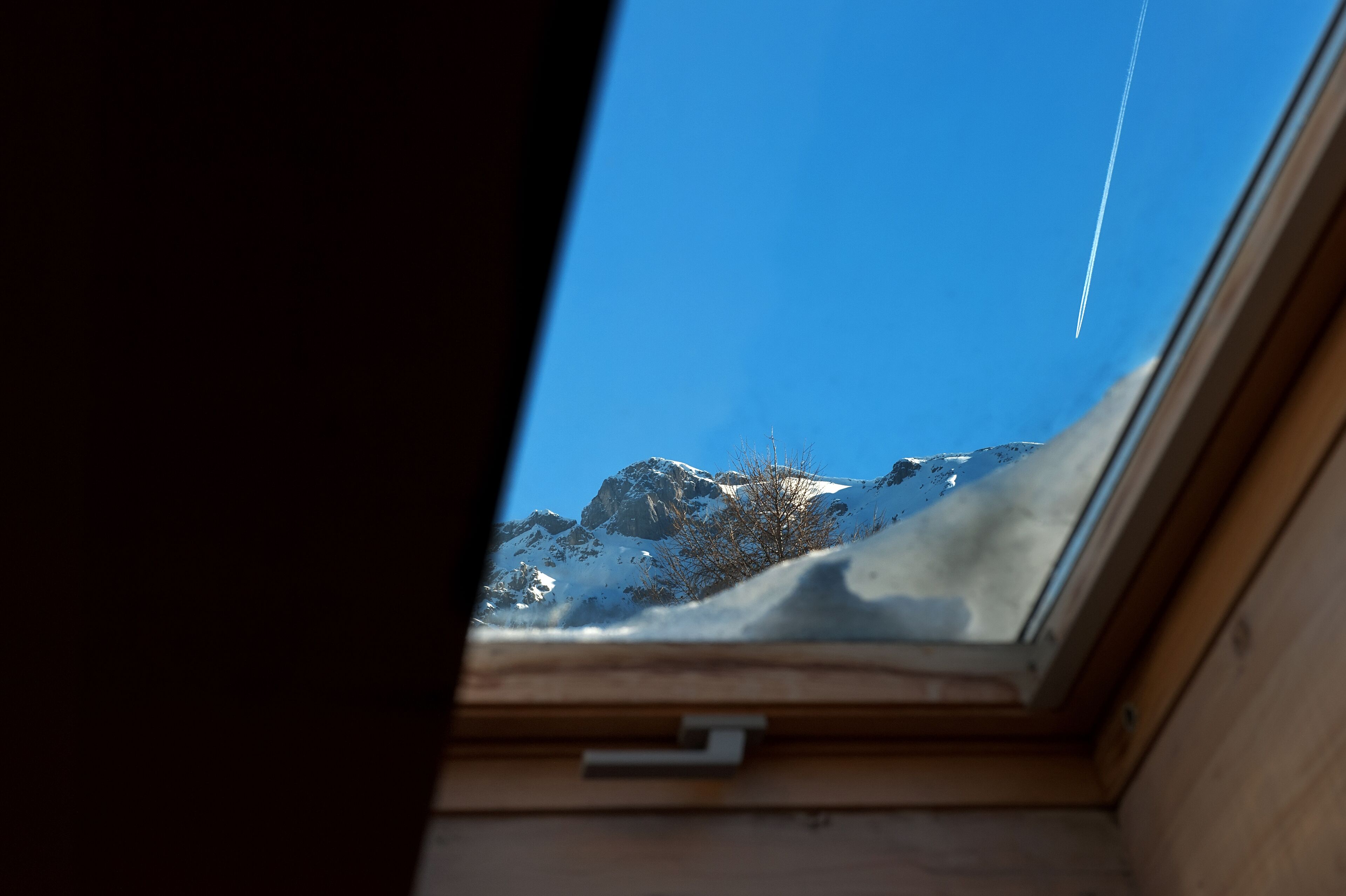 Un tragaluz con vistas a montañas nevadas y cielo despejado.