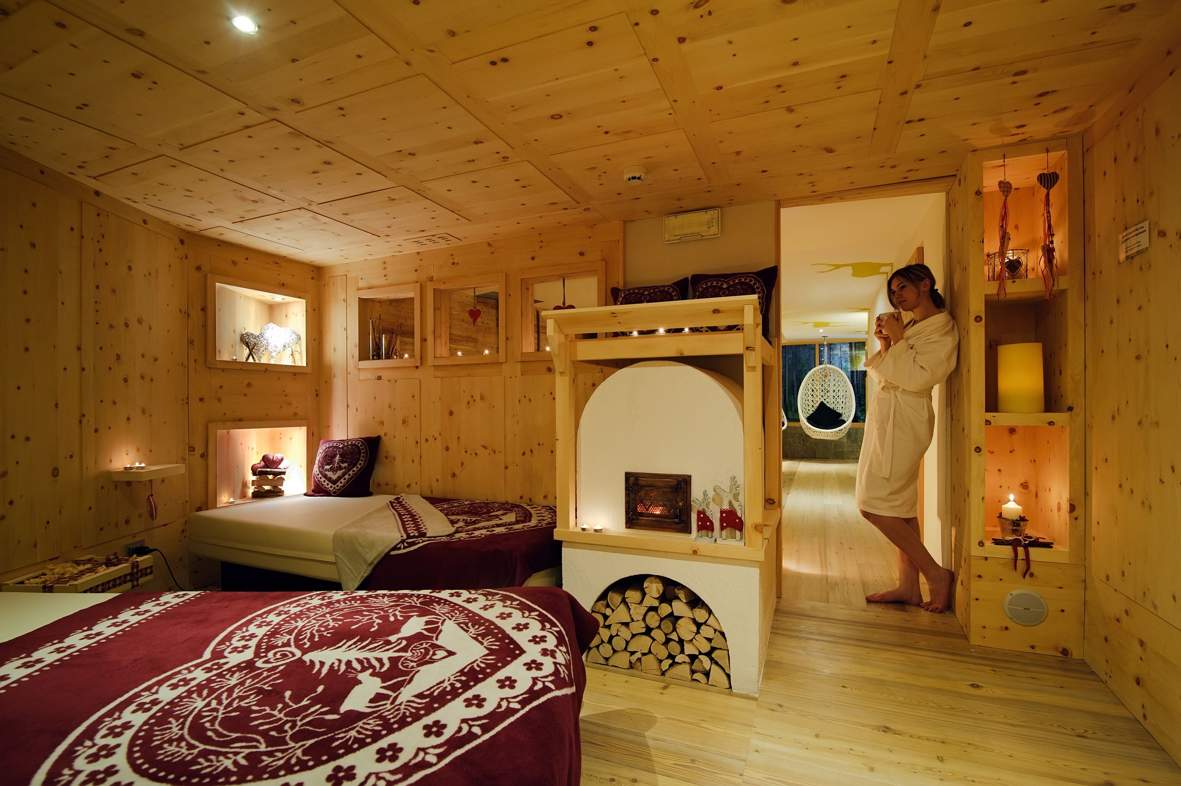 Um quarto em estilo cabana de madeira, com uma cama, uma pequena lareira e um banco de madeira.