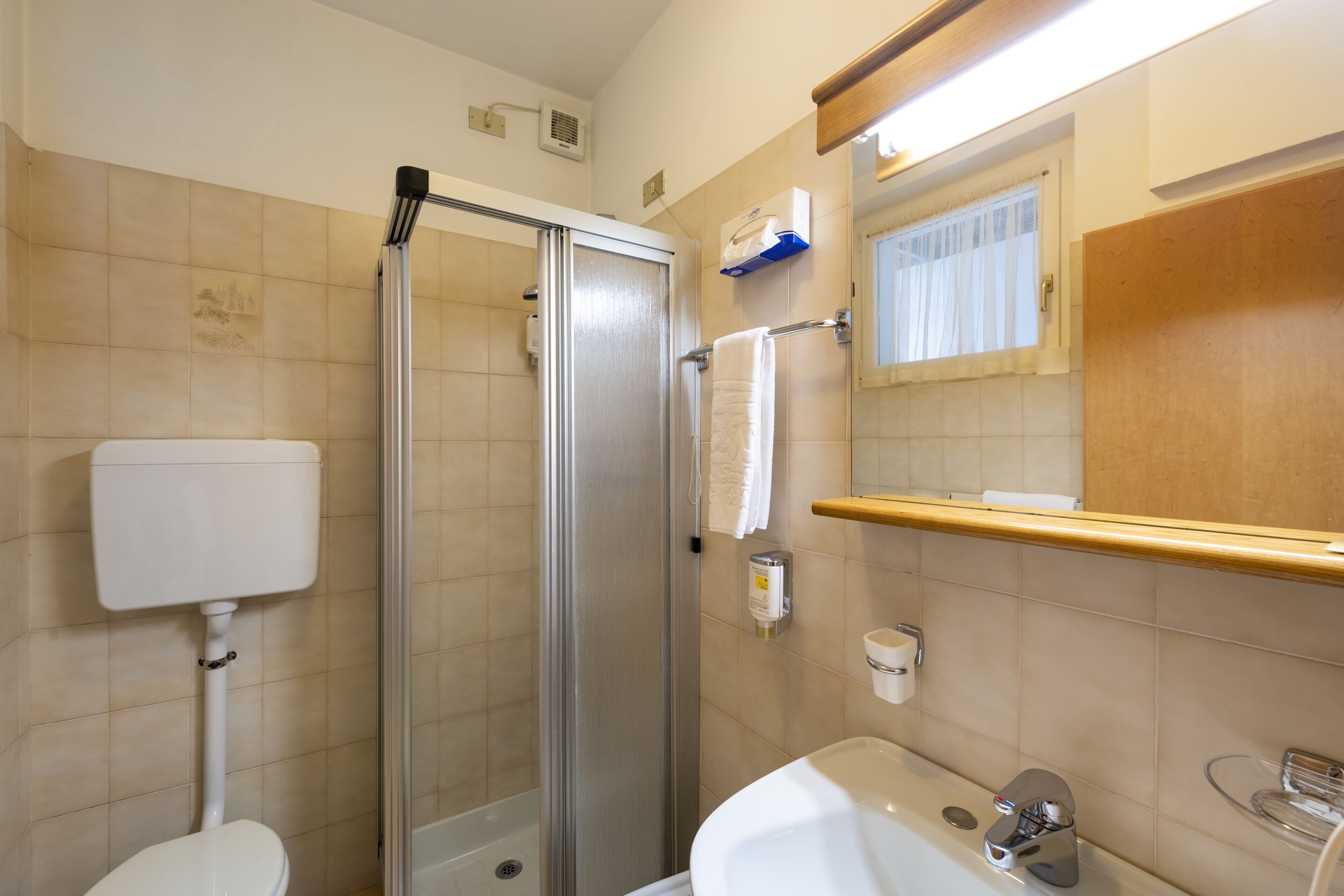 Une salle de bain comprenant des toilettes, une douche, un lavabo et un miroir.