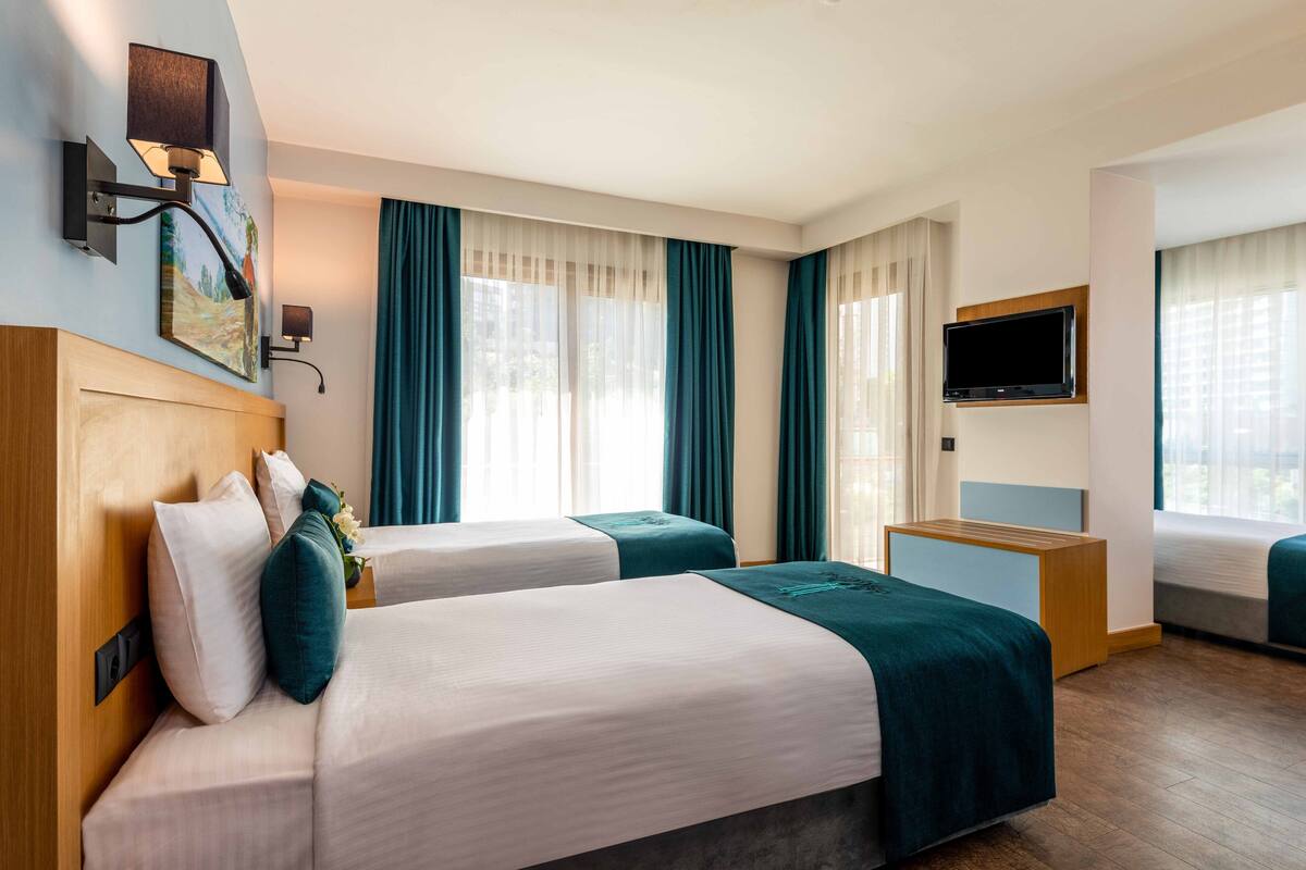 A hotel room with two beds, a flat-screen TV, and a painting on the wall.