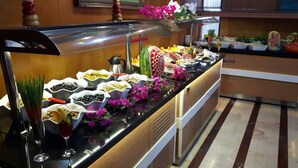 Ein Buffet mit verschiedenen Speisen und Getränken, einer Zierpflanze und einem an der Wand befestigten Fernseher.