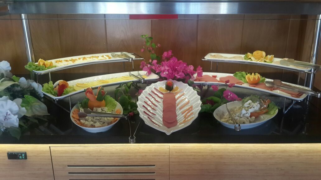 A buffet with various food items and a decorative flower arrangement.