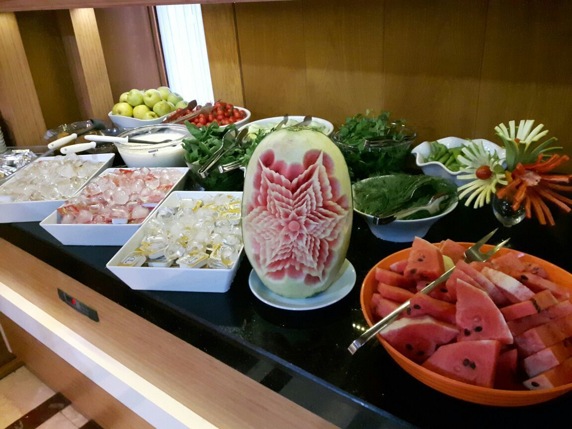 A buffet table with various food items including a carved watermelon, bowls of fruits, and vegetables.
