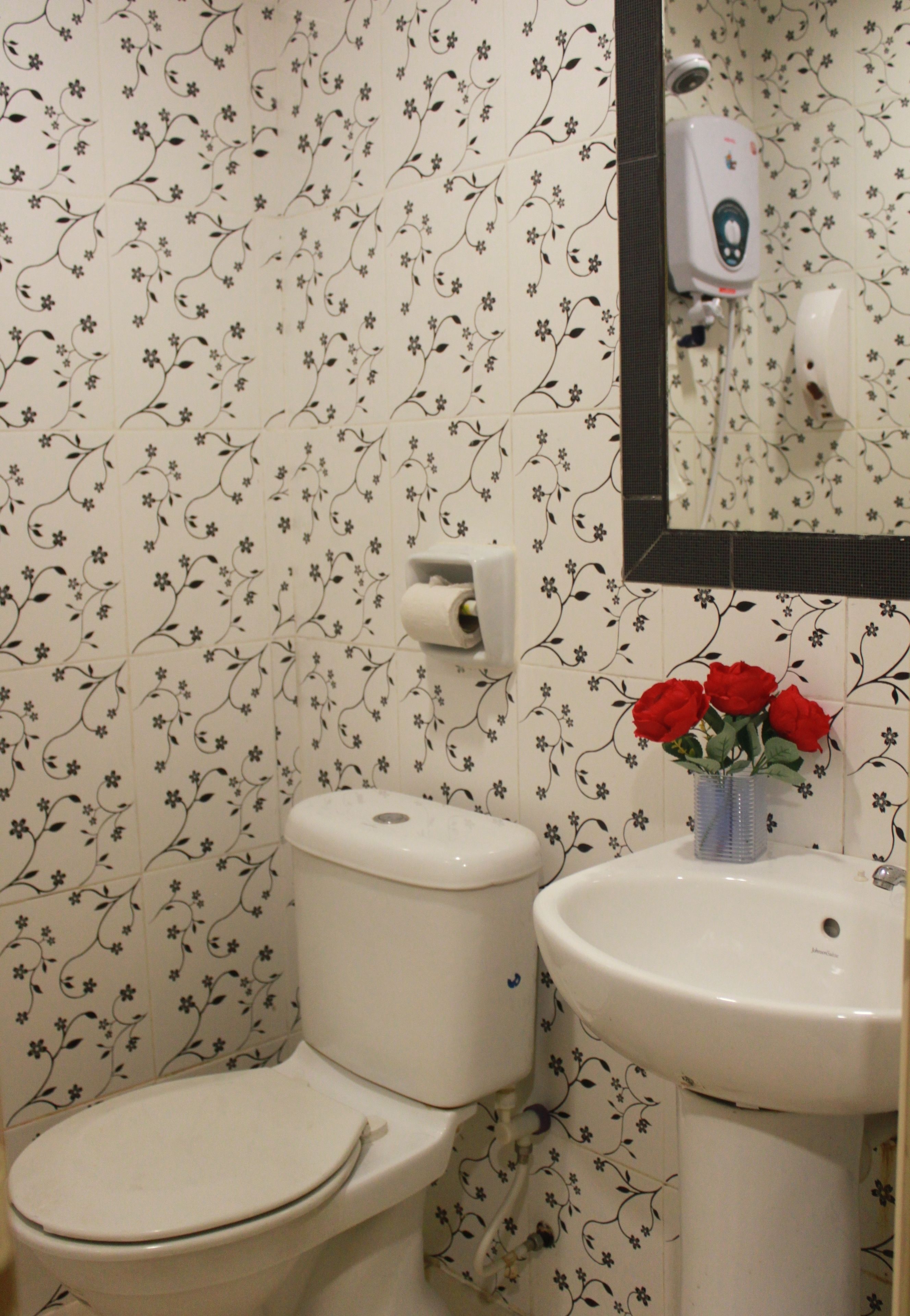 A bathroom with a toilet, sink, and a mirror.