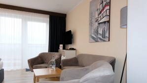 Een moderne woonkamer met een bank, een salontafel en een flatscreen televisie aan de muur.