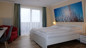 Een hotelkamer met een bed, een bureau, een stoel, een nachtkastje en een schilderij aan de muur.