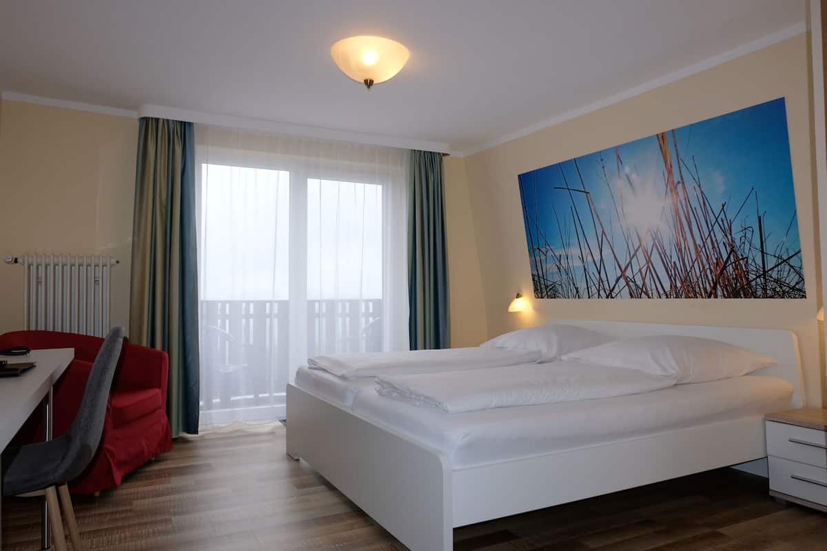 Ein Hotelzimmer mit Bett, Schreibtisch, Stuhl, Nachttisch und einem Bild an der Wand.