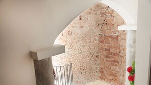 Eine Treppe führt zu einer Backsteinmauer mit einem Metallgeländer und einer Säule mit roten Blumen.