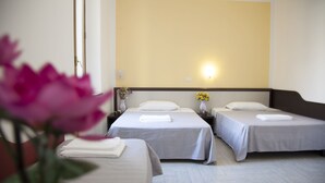 Ein Hotelzimmer mit zwei Betten, einem Nachttisch mit Lampe und einer Wandleuchte.