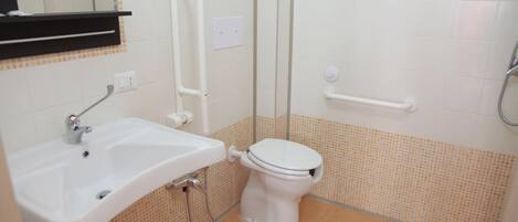 A bathroom with a white sink, toilet, and shower area.