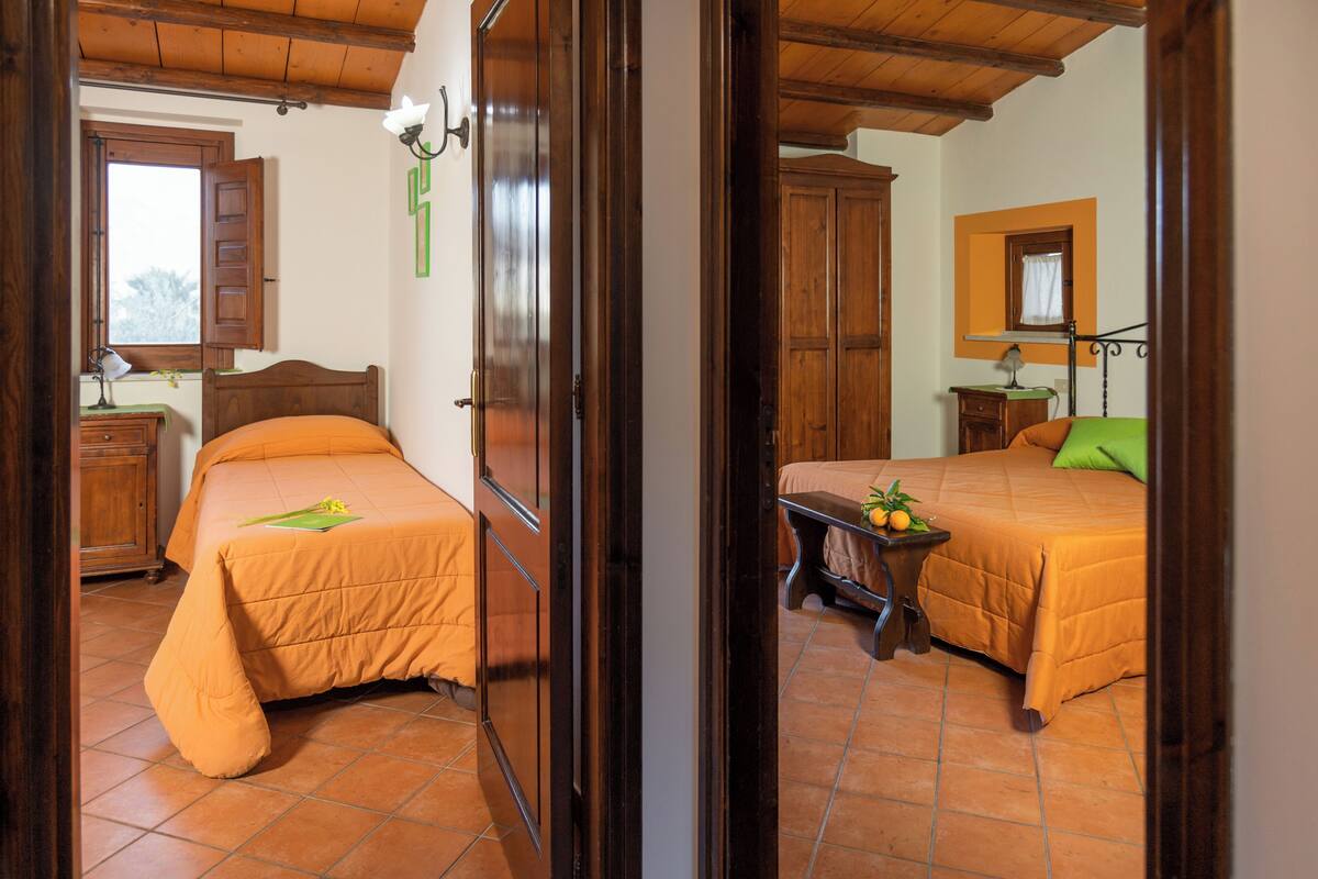 Quarto com duas camas, móveis de madeira e uma janela.