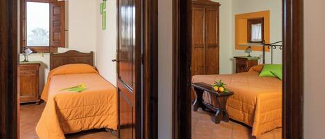 A bedroom with two beds, wooden furniture, and a window.