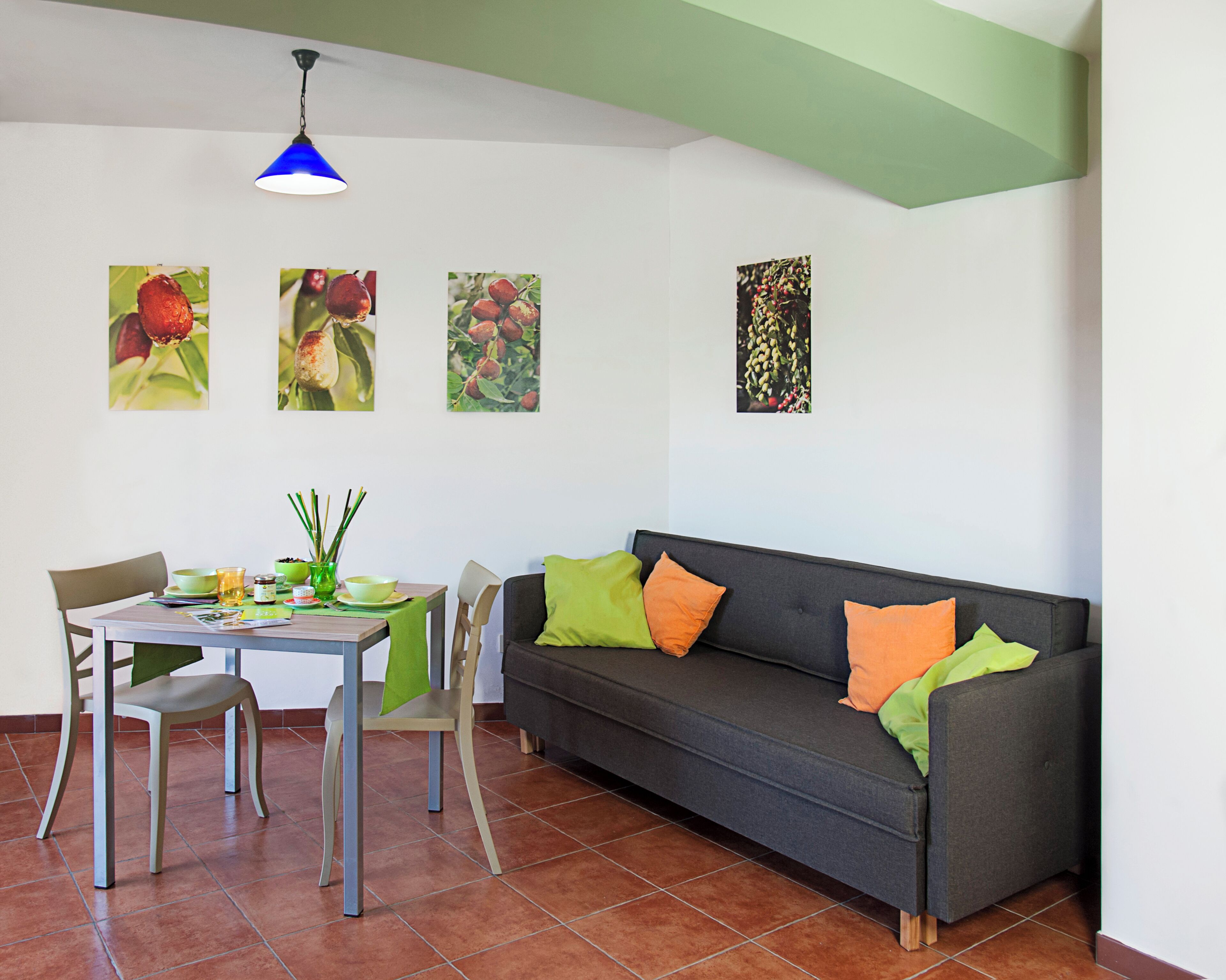 Un salon comprenant une table à manger, deux chaises, un canapé avec des coussins et quatre tableaux accrochés au mur.
