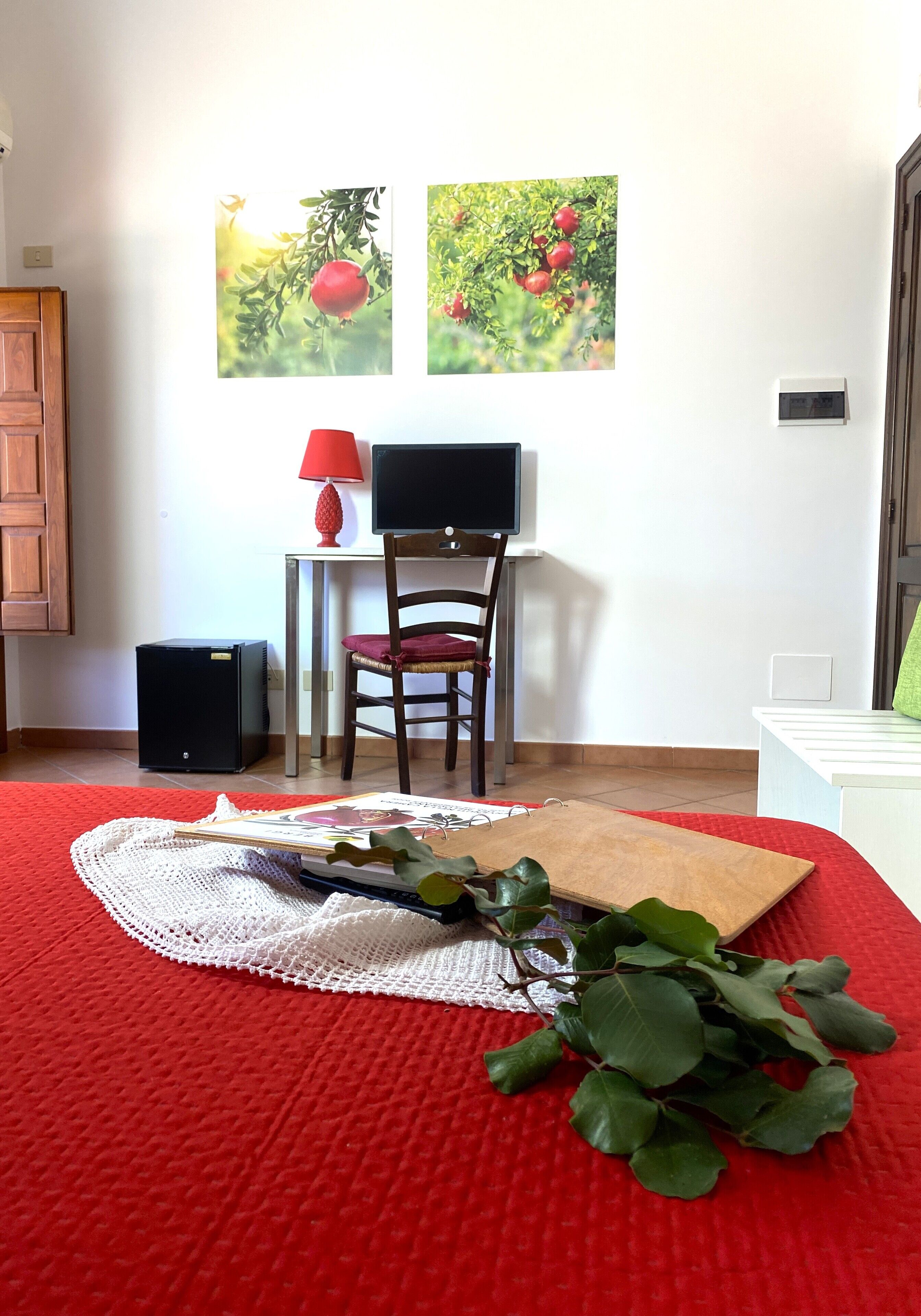 A room with a red carpet, a wooden chair, a desk with a lamp, and two framed pictures on the wall.