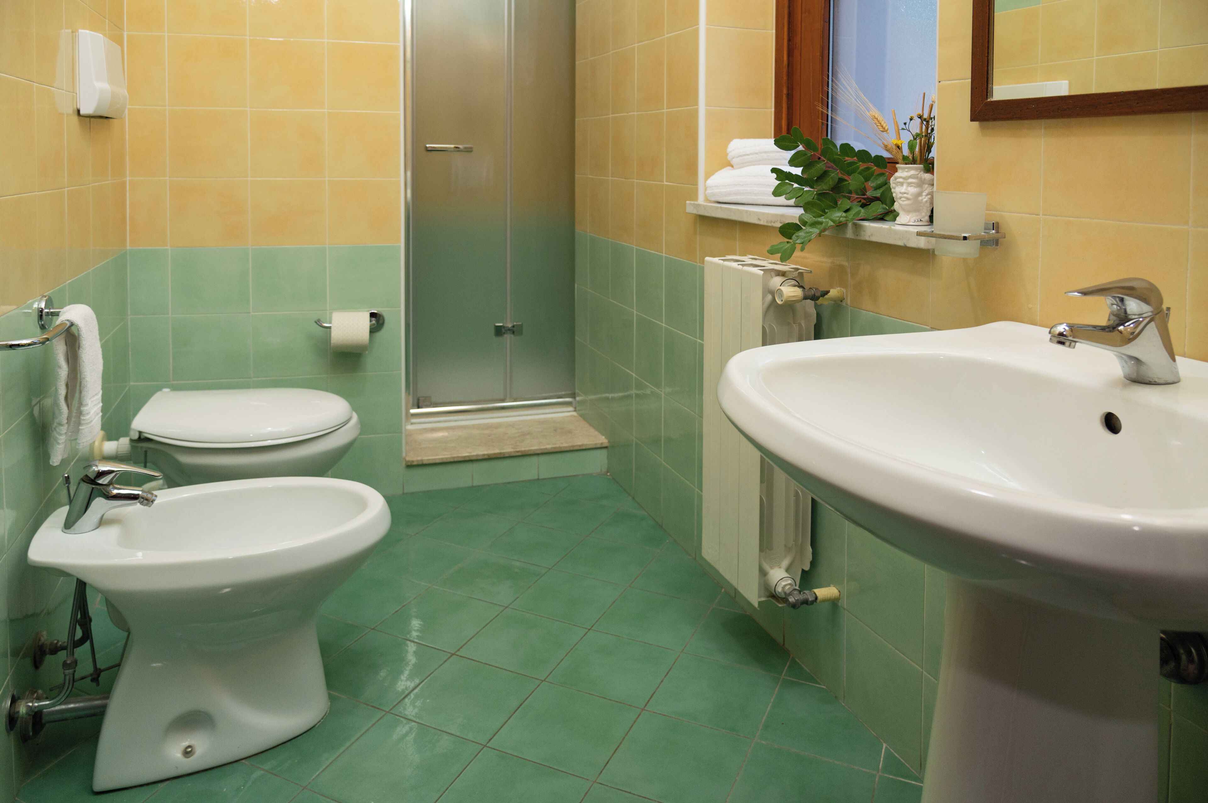 Un bagno con WC, bidet, lavandino e cabina doccia in vetro.