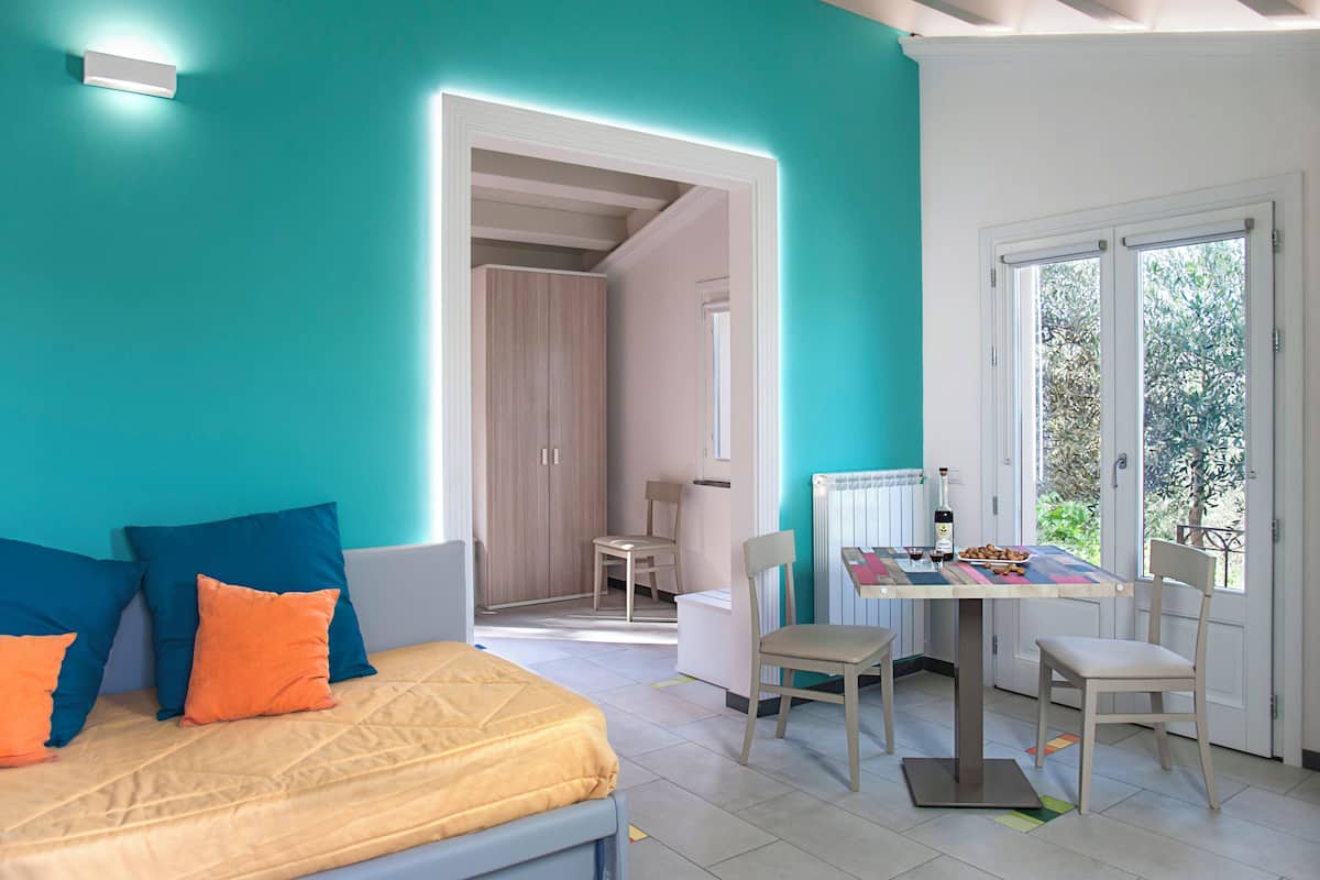 Um quarto com cama, uma mesa e cadeiras, e vista para o exterior.