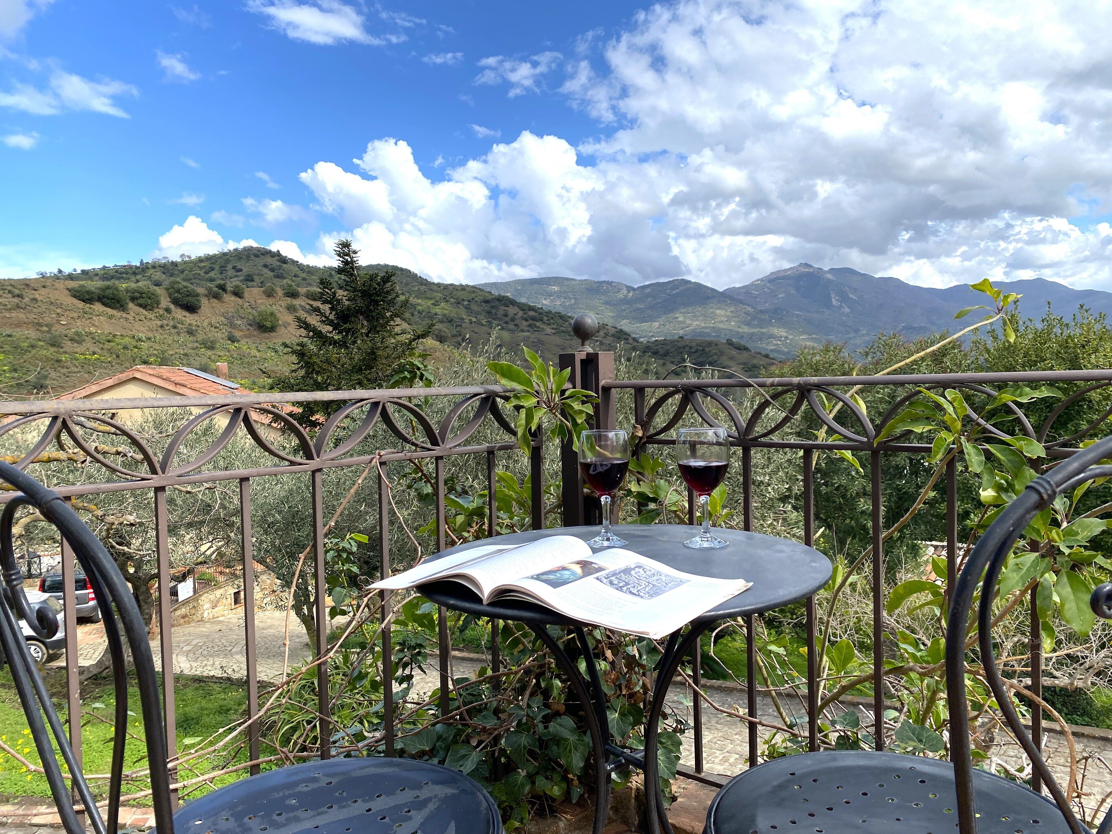 A table with two wine glasses and an open menu, set against a backdrop of mountains and a clear sky.