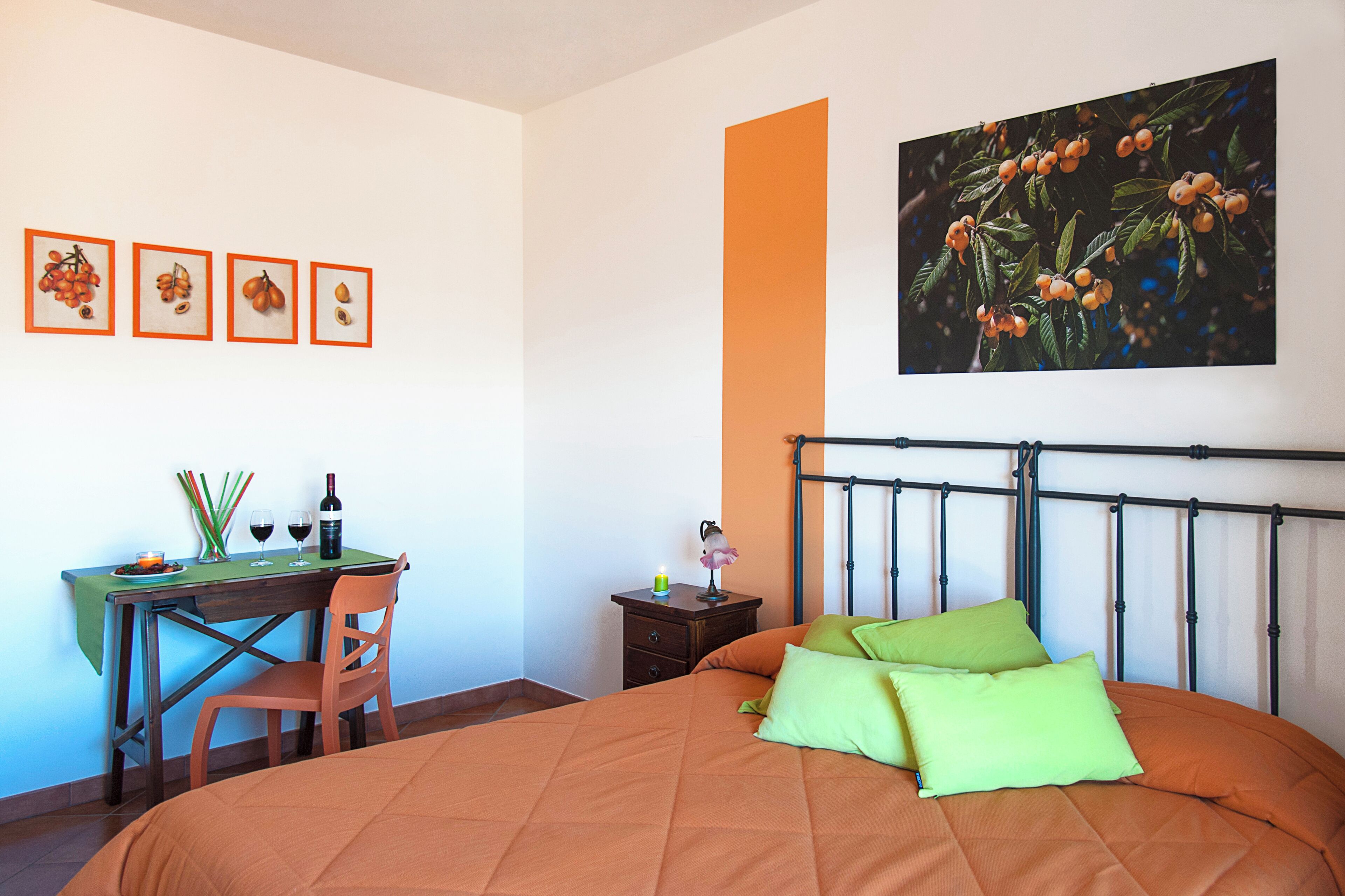 A bedroom with a bed, a desk, and a chair. There are framed pictures on the wall.