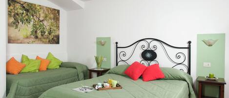 A bedroom with two beds, green bedding, a breakfast tray, and a painting on the wall.