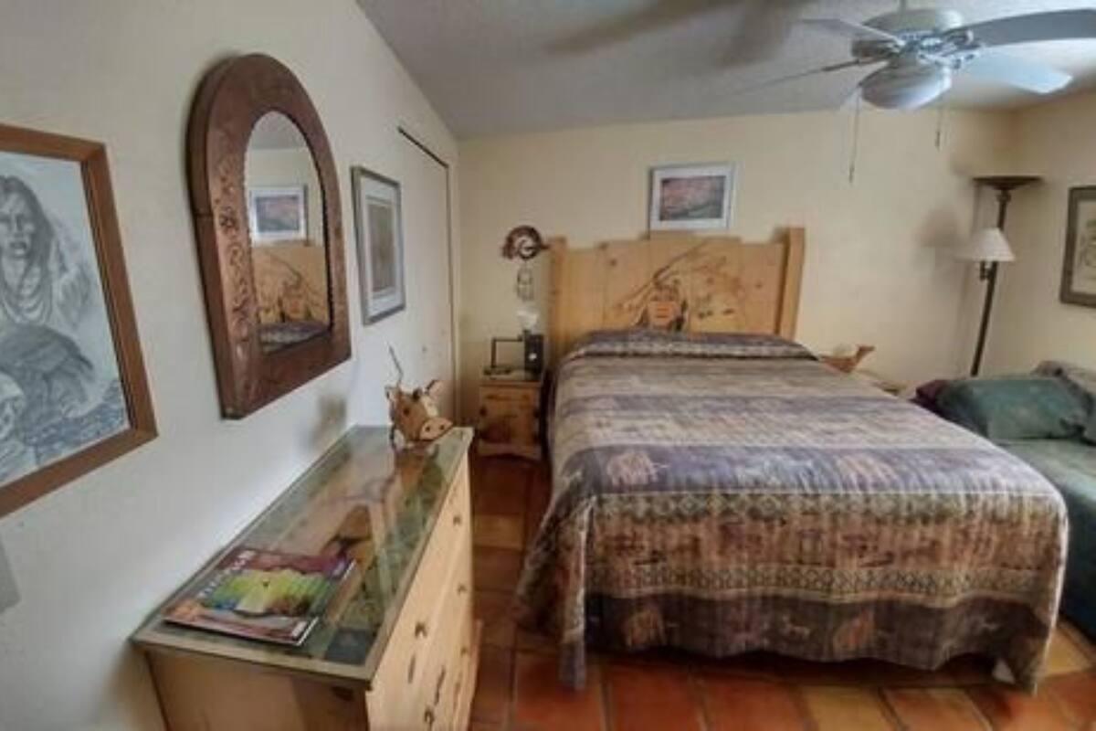 A bedroom with a bed, a dresser, a mirror, and a ceiling fan.