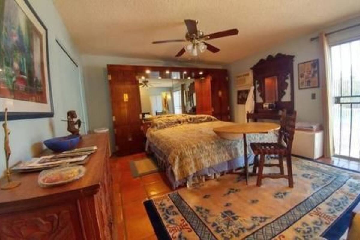 A room with a bed, a desk, a chair, a ceiling fan, and a window.