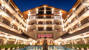 Un hotel de varios pisos con un patio central, una fuente y balcones.