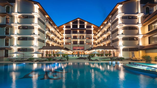 Un hotel de varios pisos con una piscina al frente.