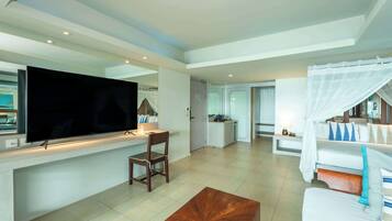 Et moderne hotelværelse med et fladskærms-tv, et spiseområde, en sofa og en seng med himmelseng.