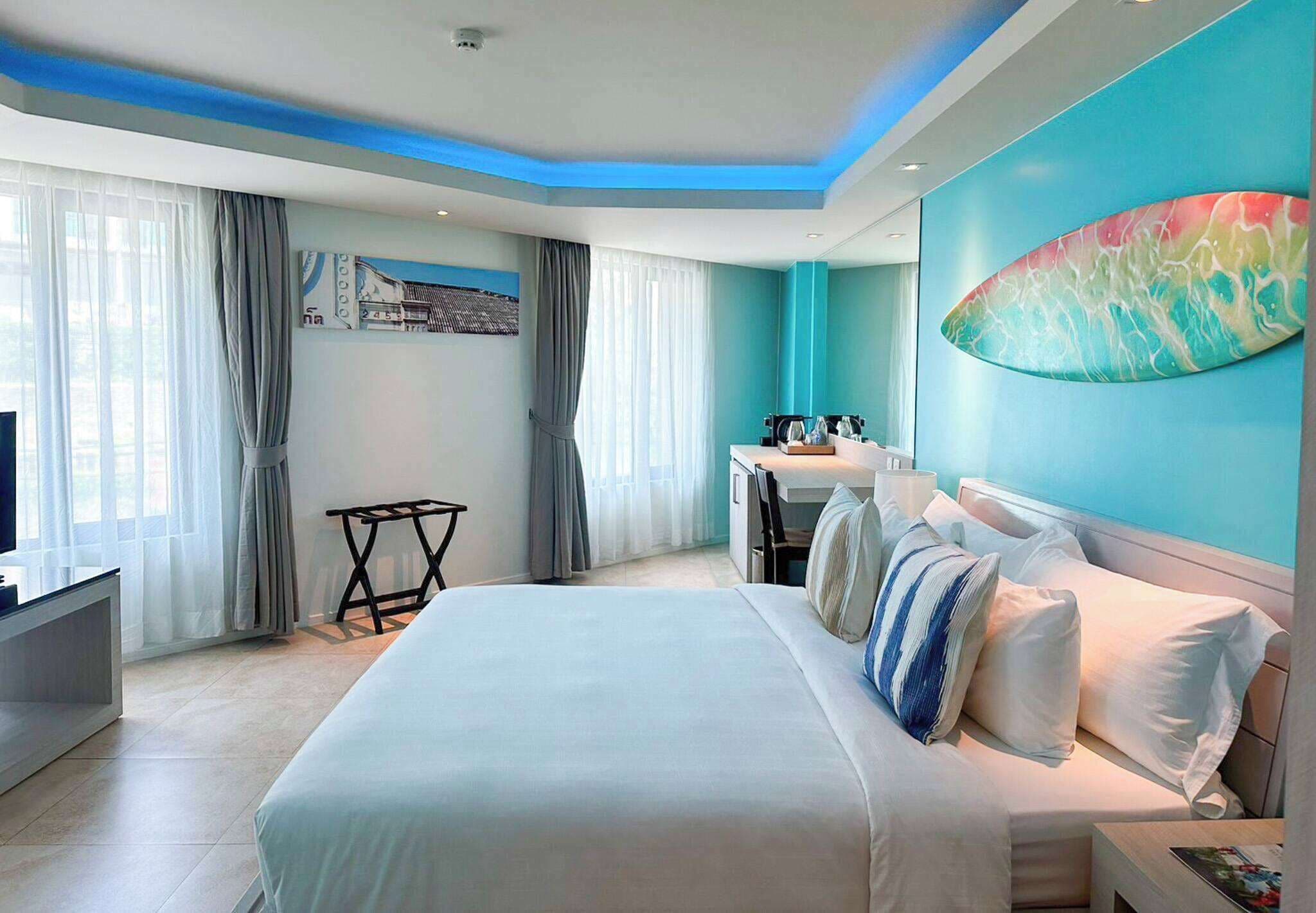 A modern hotel room with a large bed, a desk, and a dining area.
