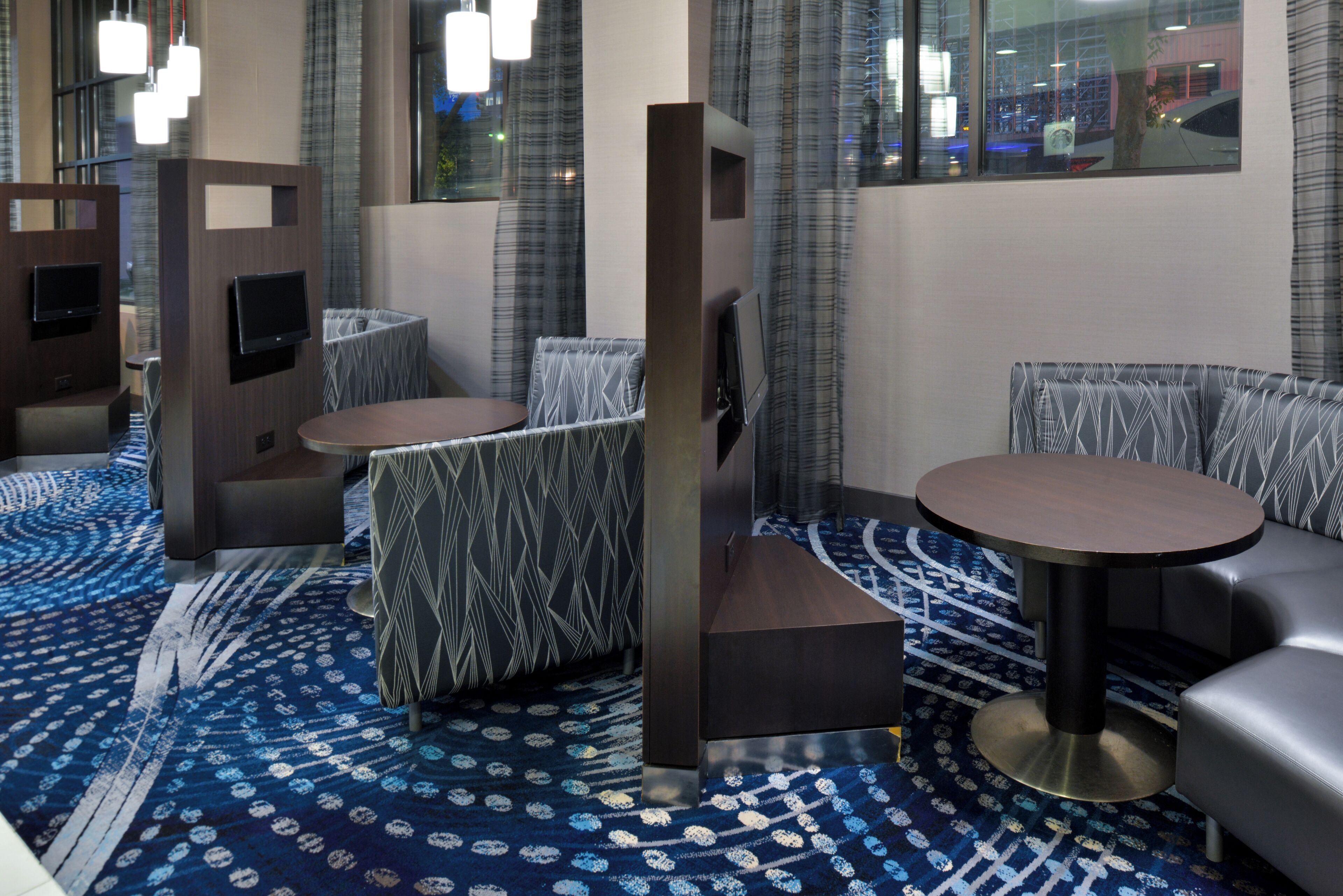 A modern lounge area with seating arrangements, including sofas and tables, and a patterned carpet.