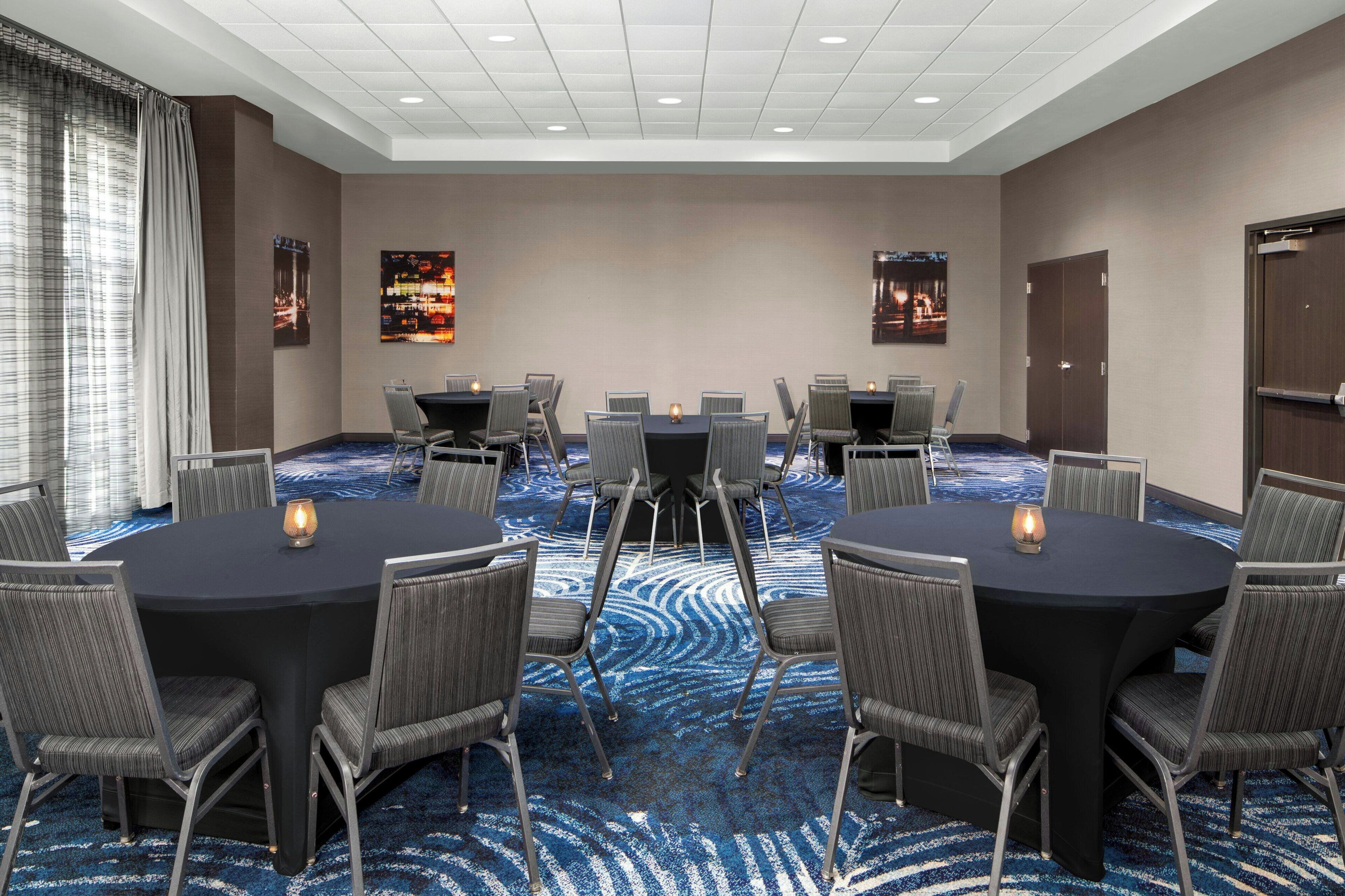 A conference room with a large oval table, surrounded by chairs, and a carpeted floor.