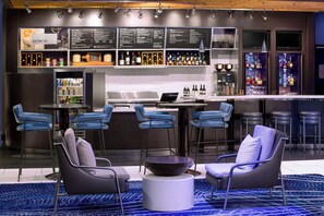 Zona de bar moderna con tablero de menú, taburetes y un área de estar con sillas y una mesa redonda.