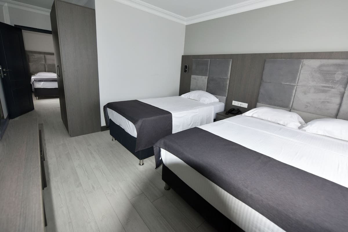 Une chambre d’hôtel avec deux lits simples, une armoire et un bureau.