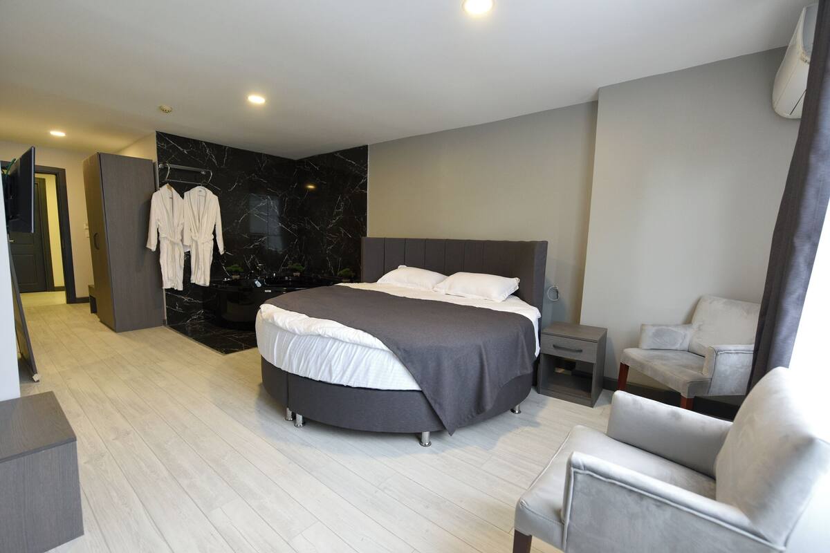 Une chambre moderne avec un grand lit, une table de chevet, une chaise et un mur en marbre.