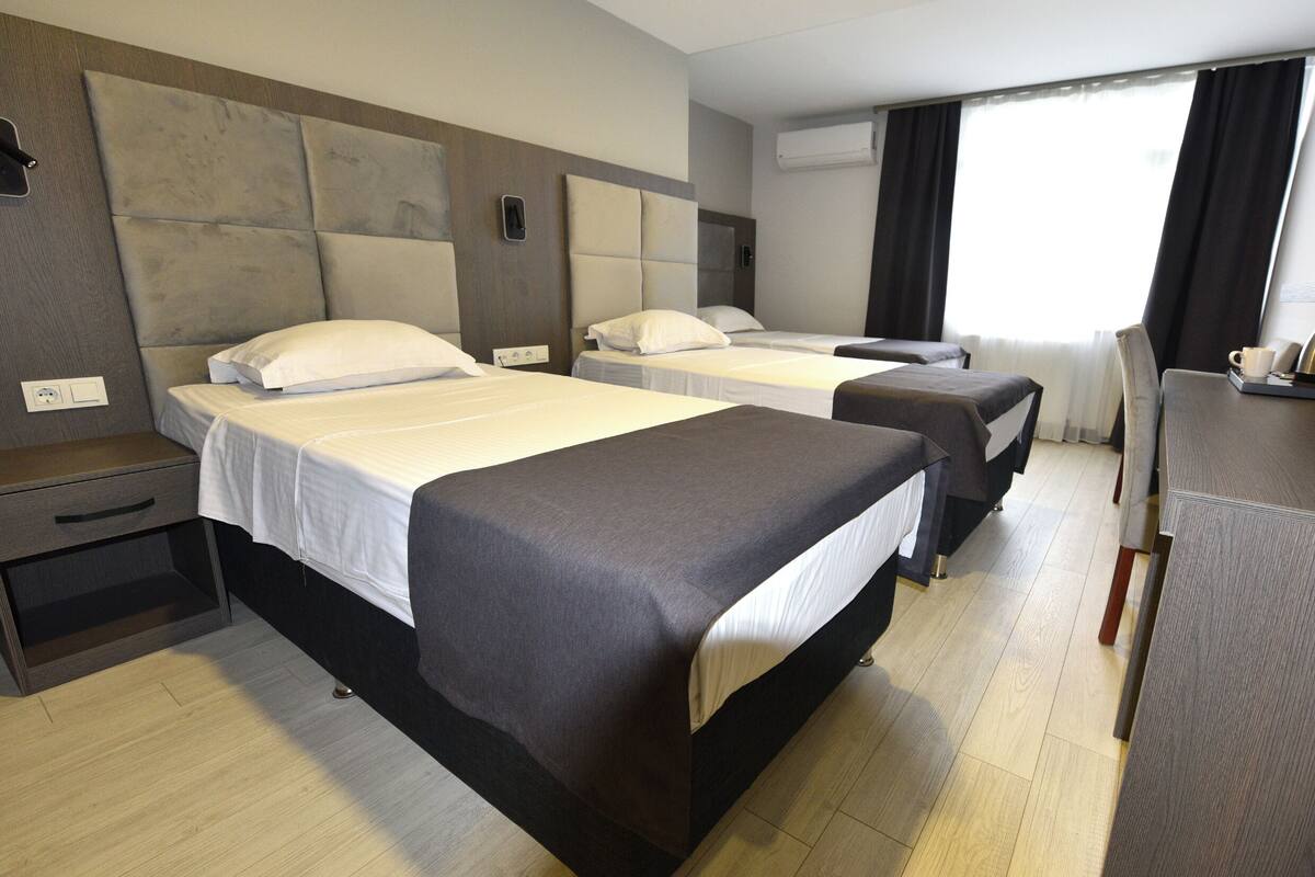 Une chambre d’hôtel avec deux lits, un bureau et une chaise.