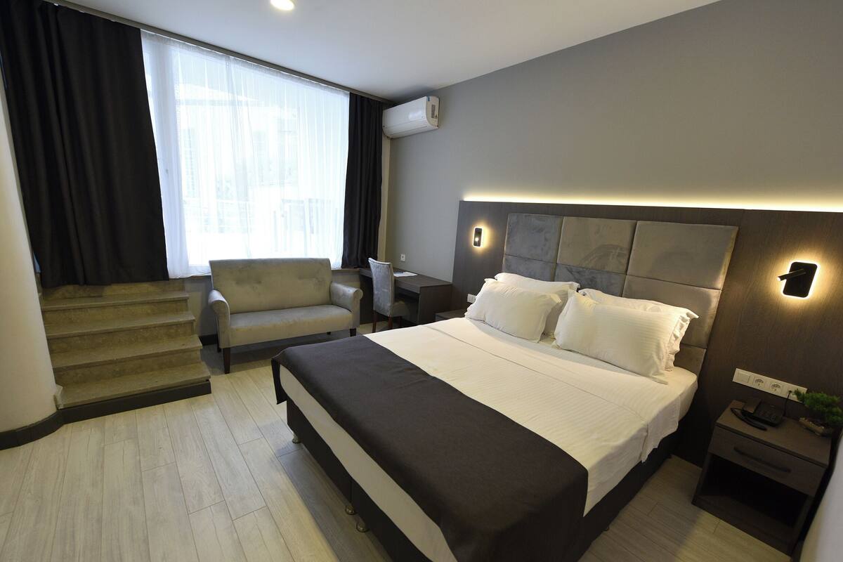 Une chambre d’hôtel moderne équipée d’un grand lit, d’un canapé, d’un bureau et d’un escalier.