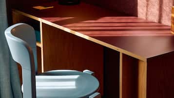 Une pièce avec un bureau en bois, une chaise, une lampe et un tapis à motifs.